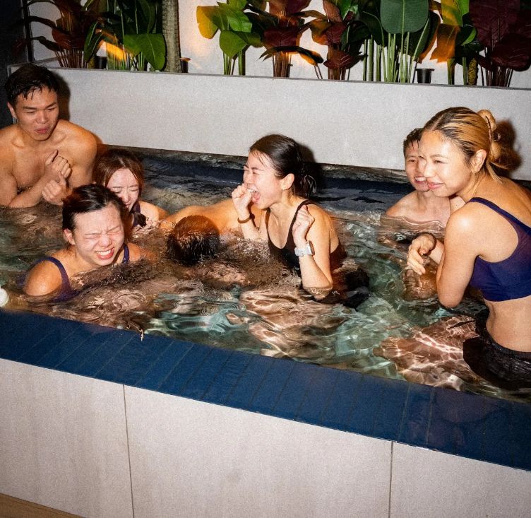 Friends bracing in the ice bath under the club sign